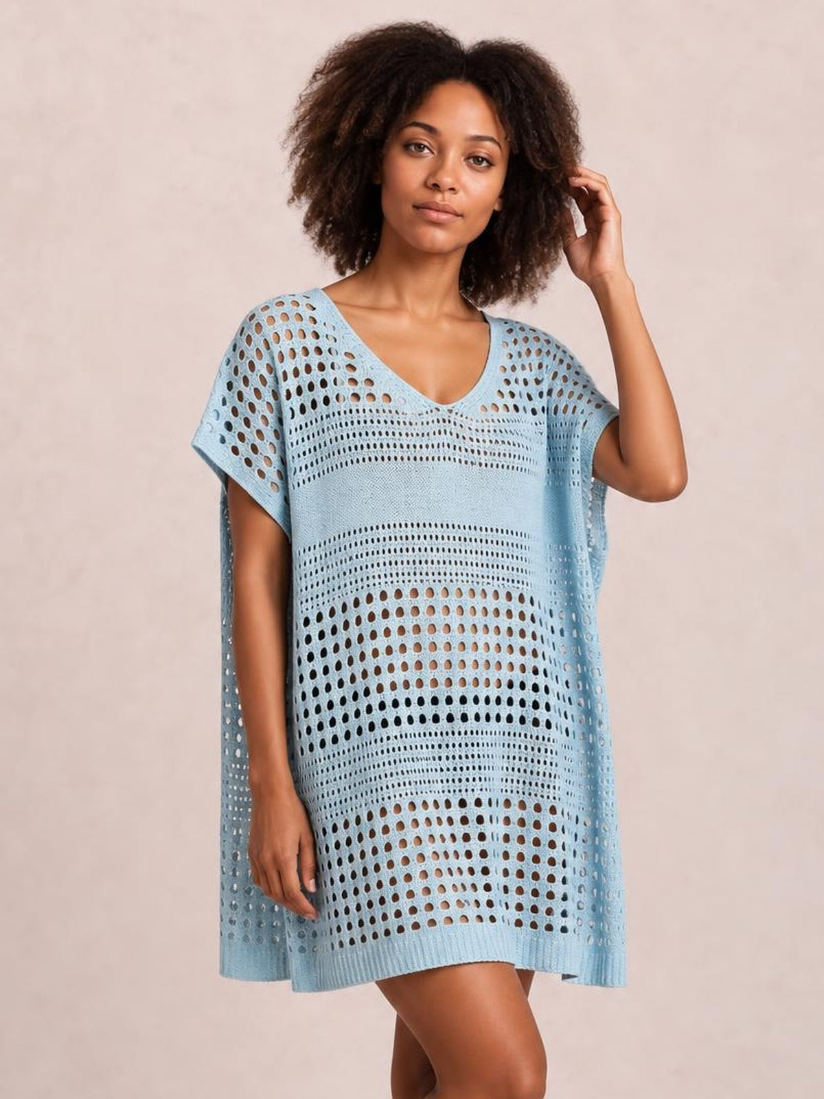 Model poses in a light blue crochet knit beach cover up dress with a relaxed boxy silhouette, V-neck, short sleeves, and openwork cutout construction.