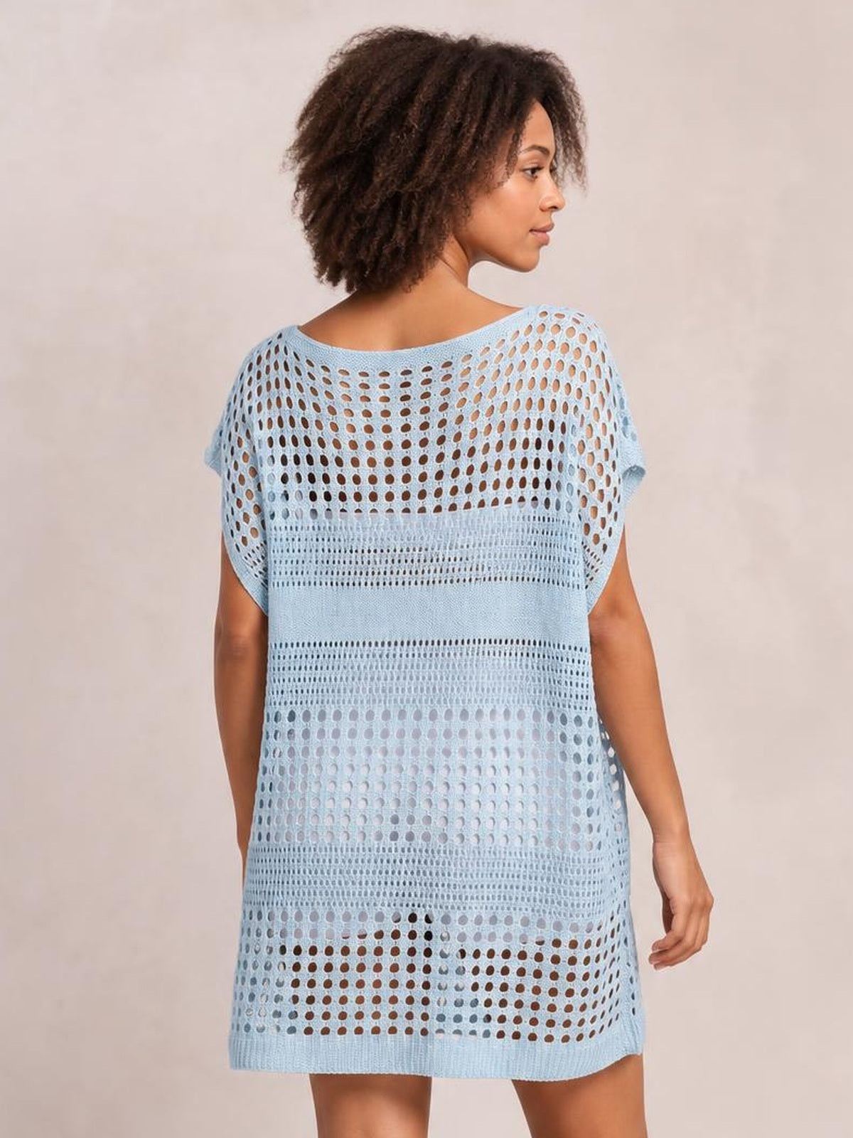 Model looks over her shoulder wearing a light blue crochet knit beach cover-up dress with short sleeves, an open cutout weave, relaxed silhouette, and straight hem.