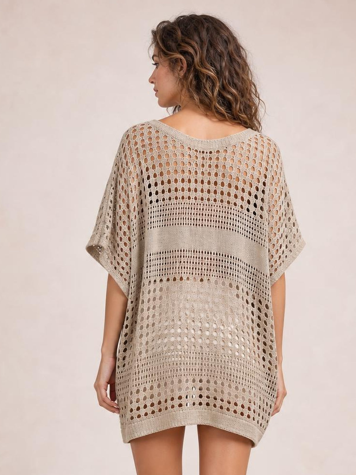 Model shown from behind wearing a beige crochet knit beach cover-up dress with openwork cutout construction, loose tunic silhouette, short sleeves, and a rounded hem.