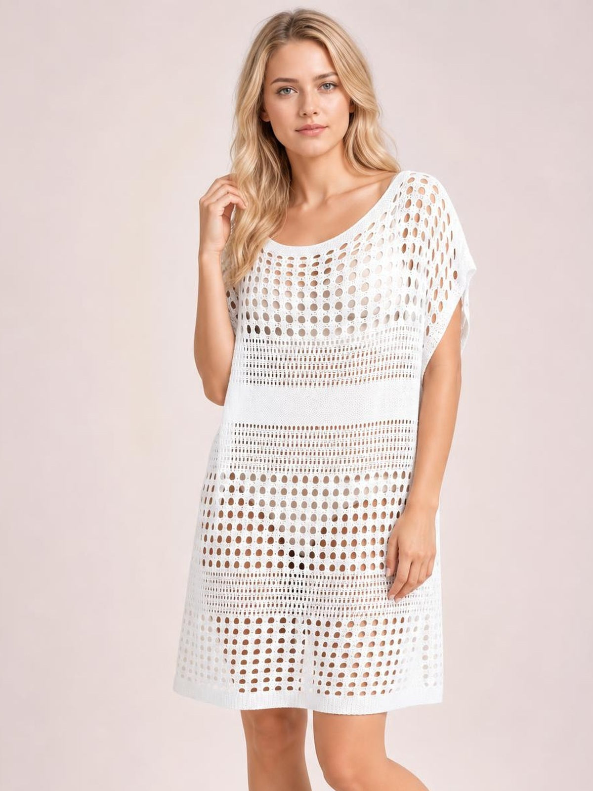 Model wearing a white crochet knit beach cover-up dress with a loose straight silhouette, scoop neckline, short sleeves, and modern cutout pattern.
