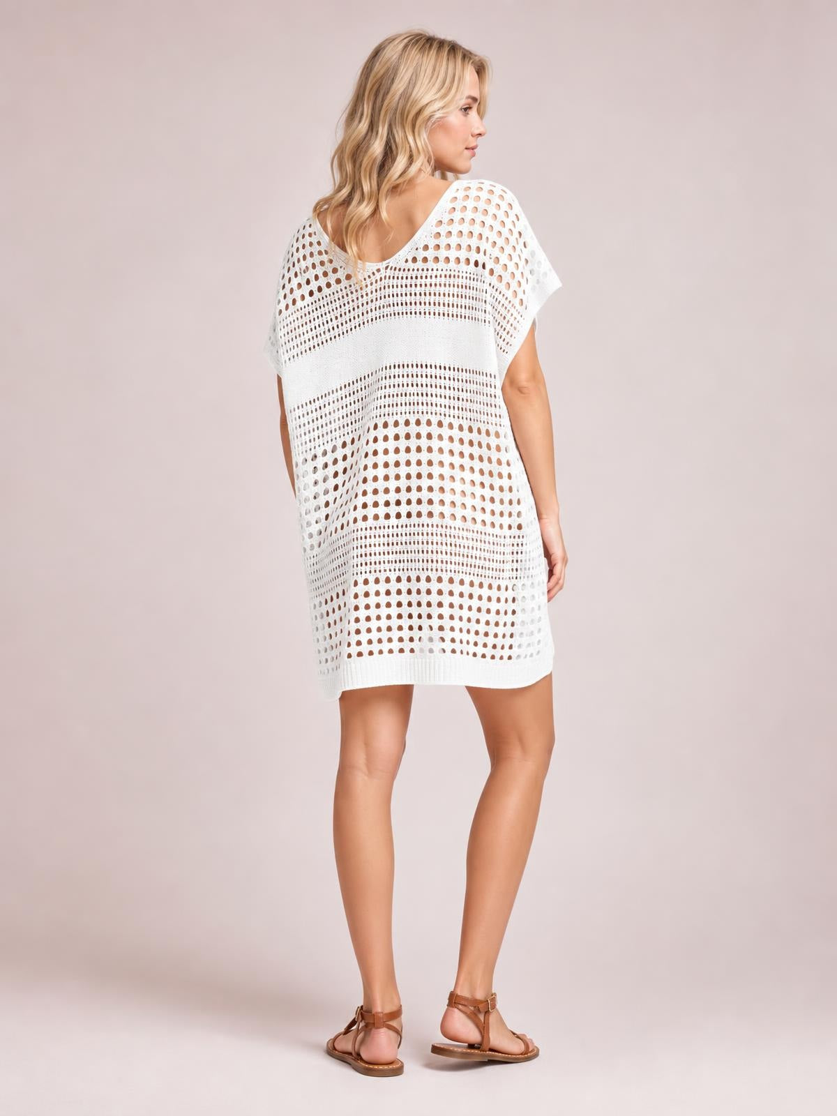 Model turns to the side in a white crochet knit beach cover up dress with open-knit cutout pattern, short sleeves, and a relaxed straight silhouette.