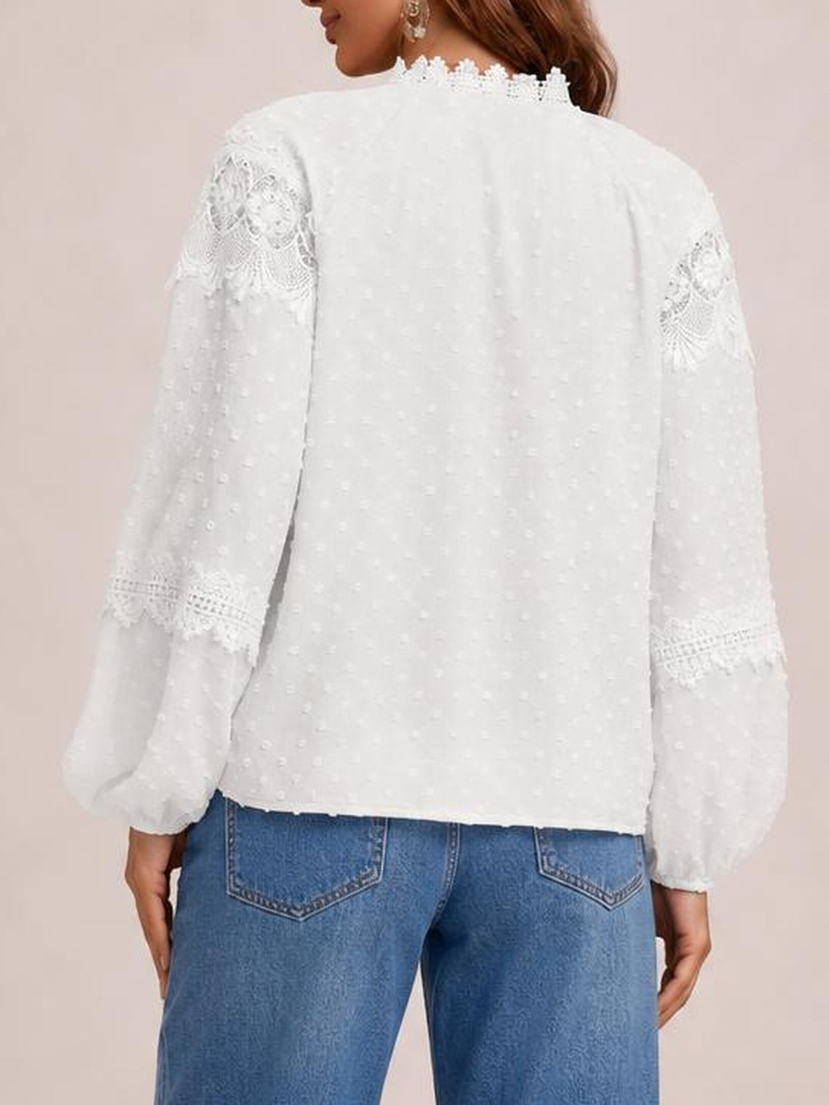 A model shown from behind wears a white semi-sheer blouse with long sleeves, textured fabric, crochet lace sleeve panels, and a ruffled neckline.