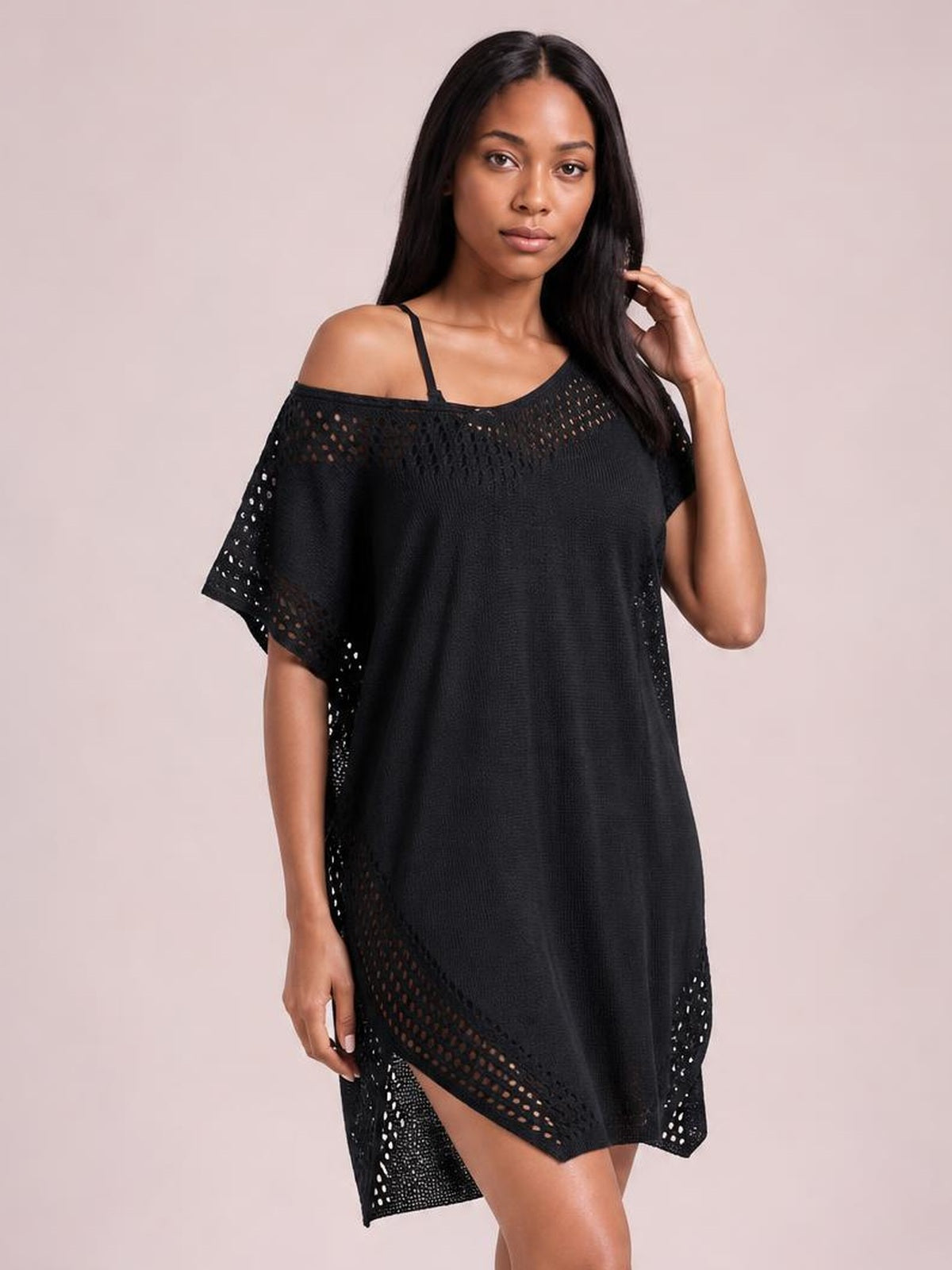 A model poses in a black crochet trim beach cover up dress with an oversized silhouette, off-shoulder neckline, cutout knit panels, and side slit.