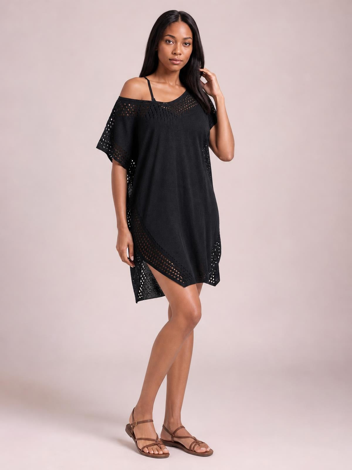 Model in a black crochet-trim beach cover-up dress with an off-shoulder neckline, sheer cutout details, loose silhouette, and side slit.