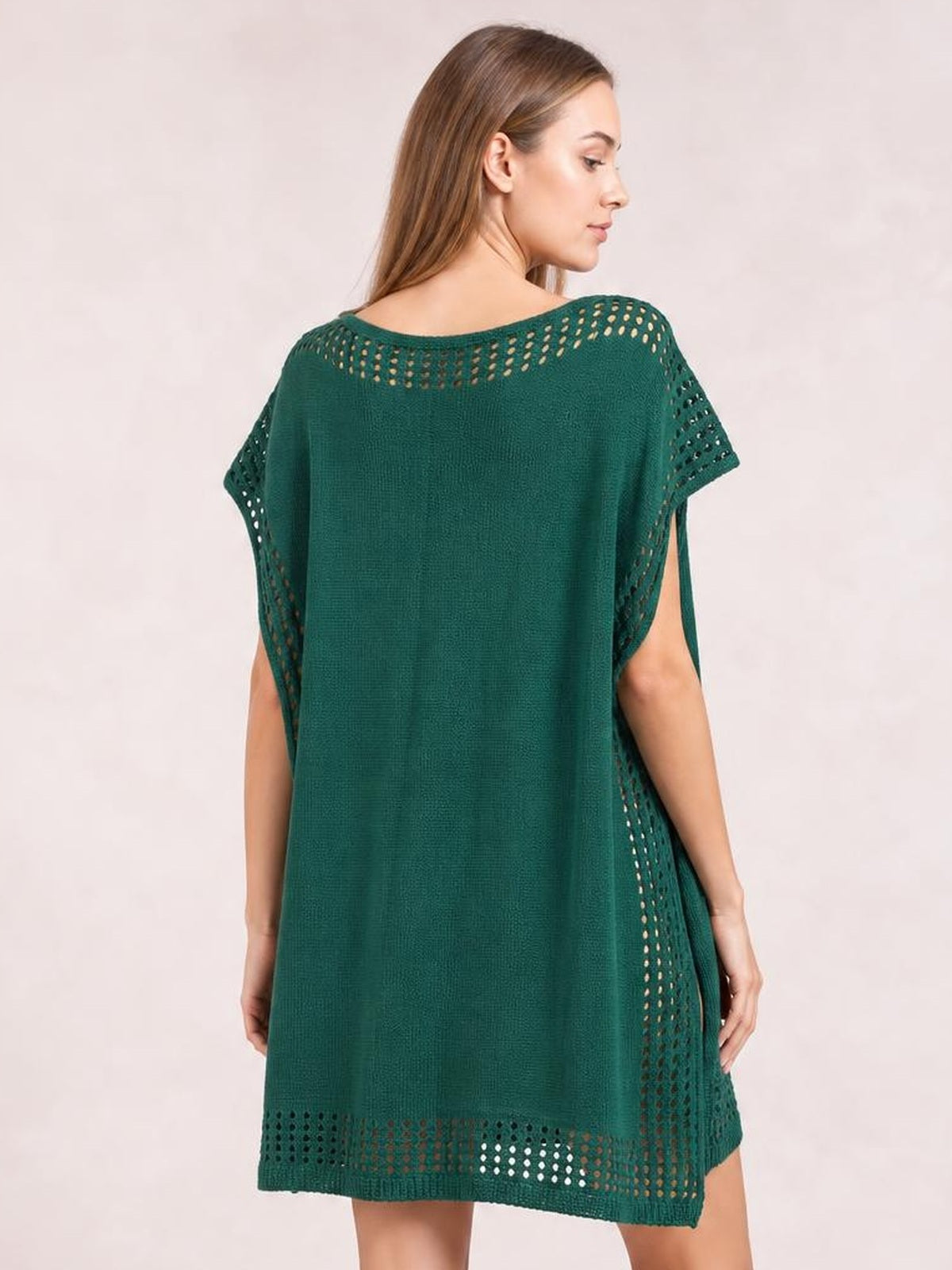 A model stands turned away in a dark green beach cover-up dress with a relaxed straight silhouette, short sleeves, openwork crochet trim, and side slit details.