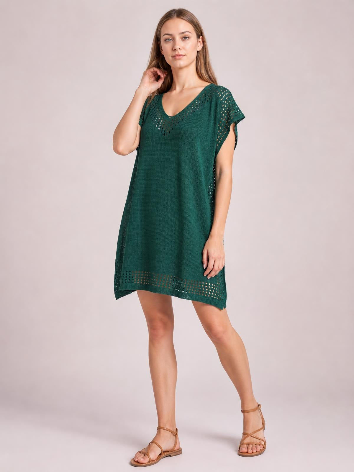 Model poses in a dark green beach cover up dress with a relaxed shift silhouette, crochet-trim cutouts, short sleeves, V-neckline, and side slits.