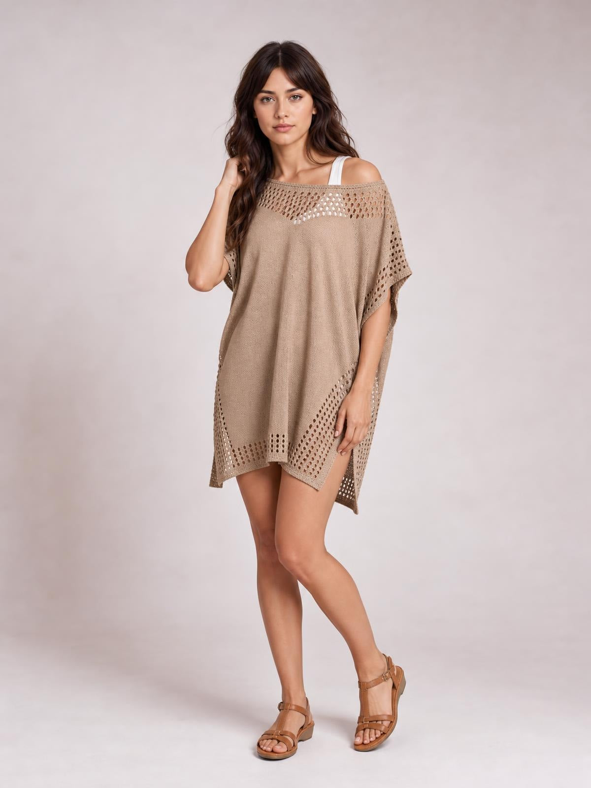 Model poses in a taupe beach cover-up dress with an off-shoulder neckline, crochet trim, openwork cutouts, side slits, and a loose silhouette.