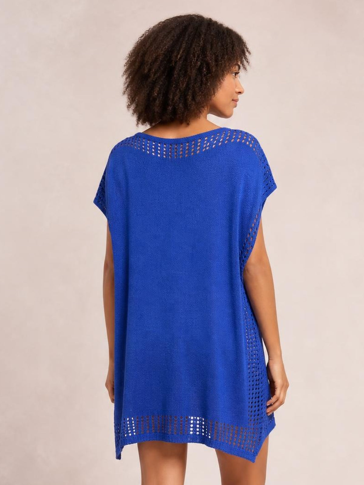 A model looks over her shoulder in a royal blue crochet trim beach cover up dress with a loose silhouette, short sleeves, cutout knit panels, and an airy hem.