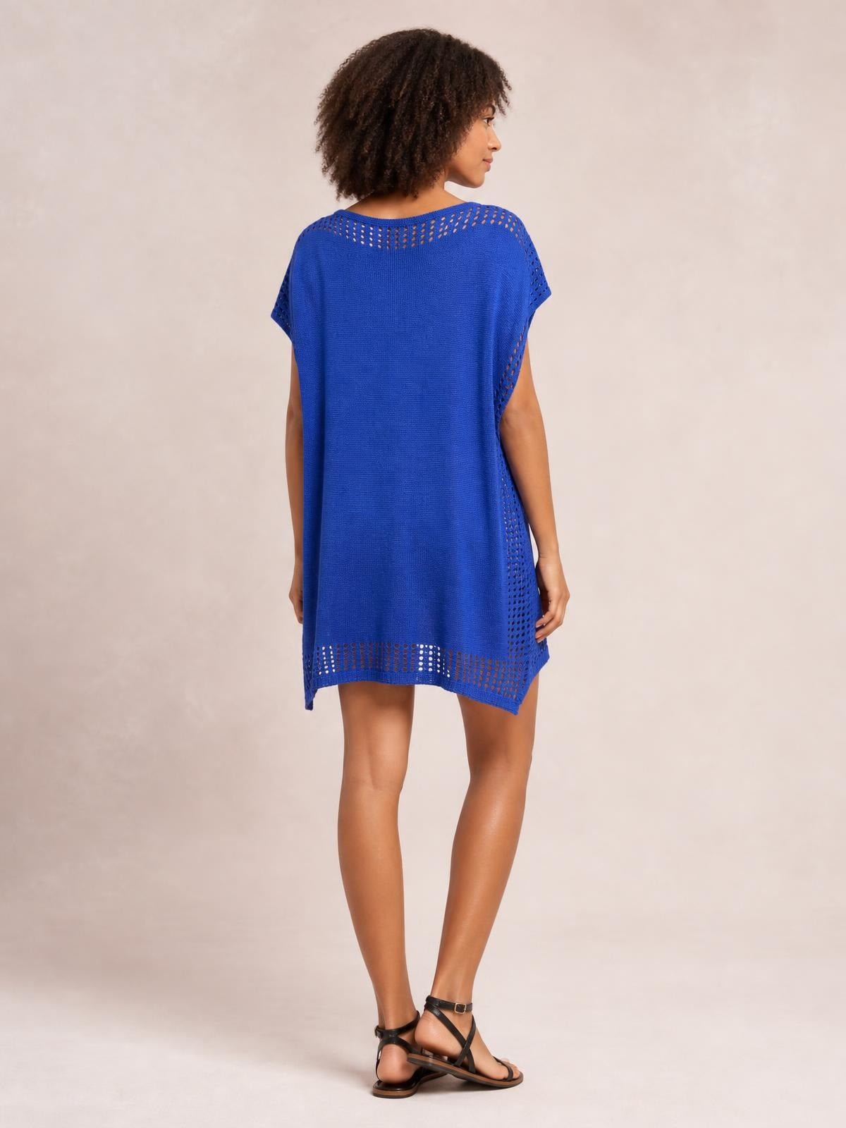 A model poses in a cobalt blue beach cover-up dress with a relaxed straight silhouette, short sleeves, cutout crochet trim, and side slit details.