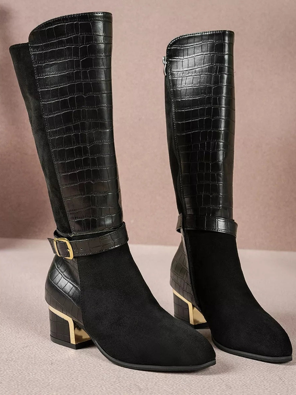 Black crocodile-texture knee-high boots feature suede-look panels, side zippers, ankle buckle straps, and low block heels with gold-tone accents.