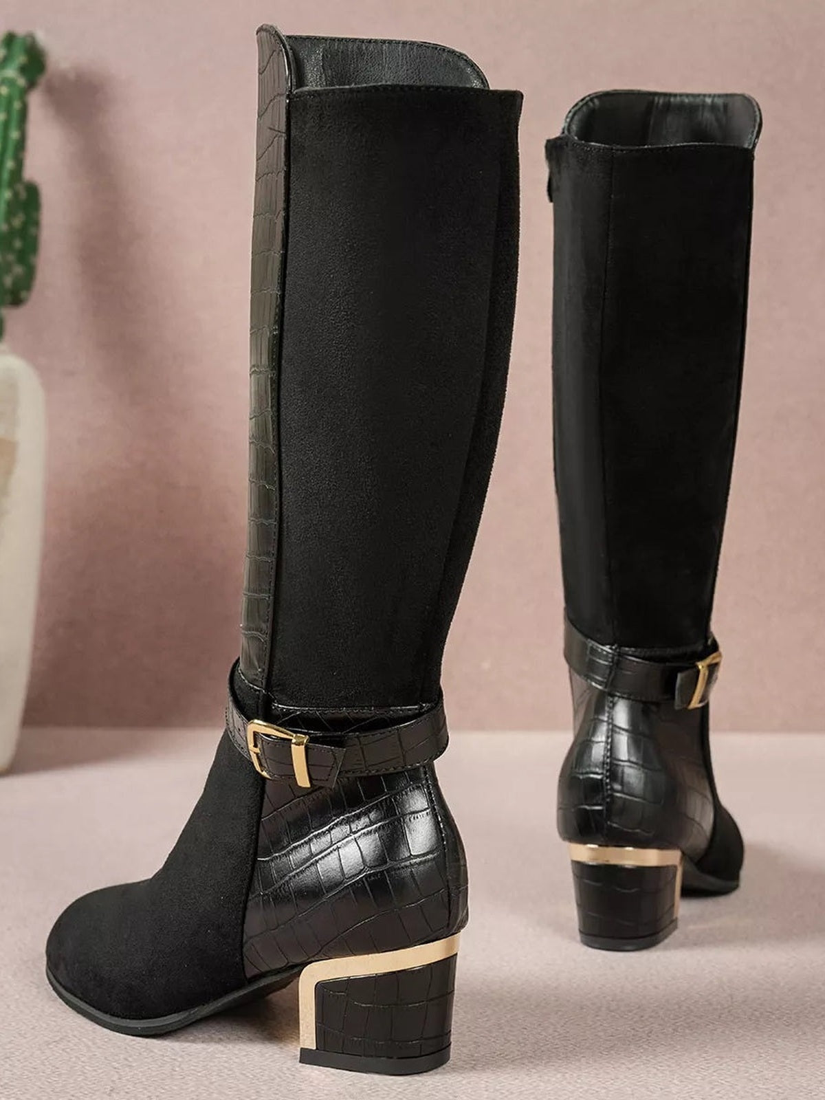 Black crocodile-texture knee-high boots feature soft suede-look shafts, buckled ankle straps, rounded toes, and sturdy low block heels.