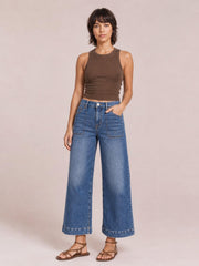 Model stands in medium-wash cropped high-rise wide-leg jeans with large front patch pockets, belt loops, and cuffed hems.