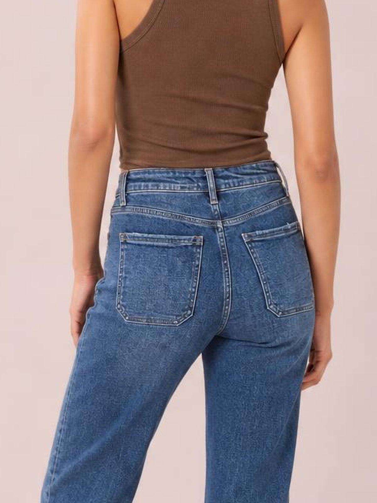 Model shown from the back in blue cropped high-rise wide-leg jeans with belt loops, contrast stitching, and two large back patch pockets.