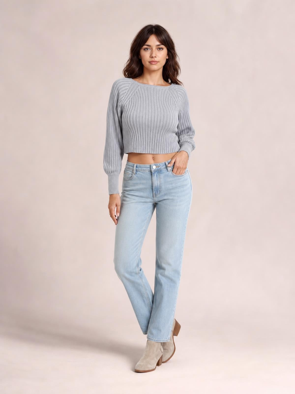 Model poses in a gray cropped round-neck ribbed pullover sweater with long raglan sleeves, fitted silhouette, and banded cuffs.