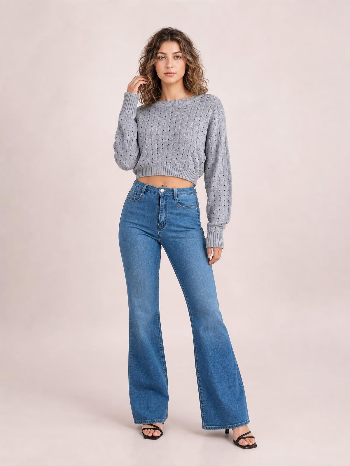 Model poses in a light gray openwork round-neck sweater with long sleeves, ribbed cuffs and hem, and a cropped, relaxed silhouette.
