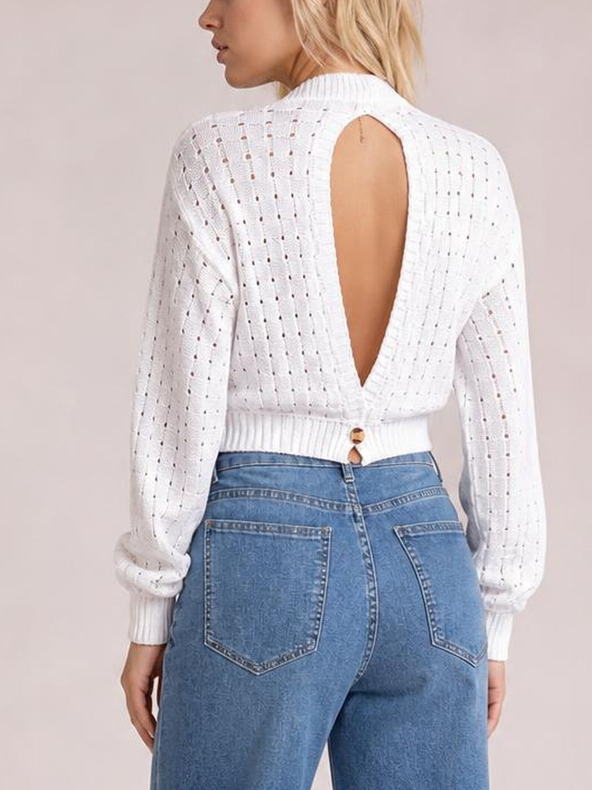 Model turned away wears a white long-sleeve openwork sweater with a round neck, ribbed cuffs and hem, and a deep cutout back.