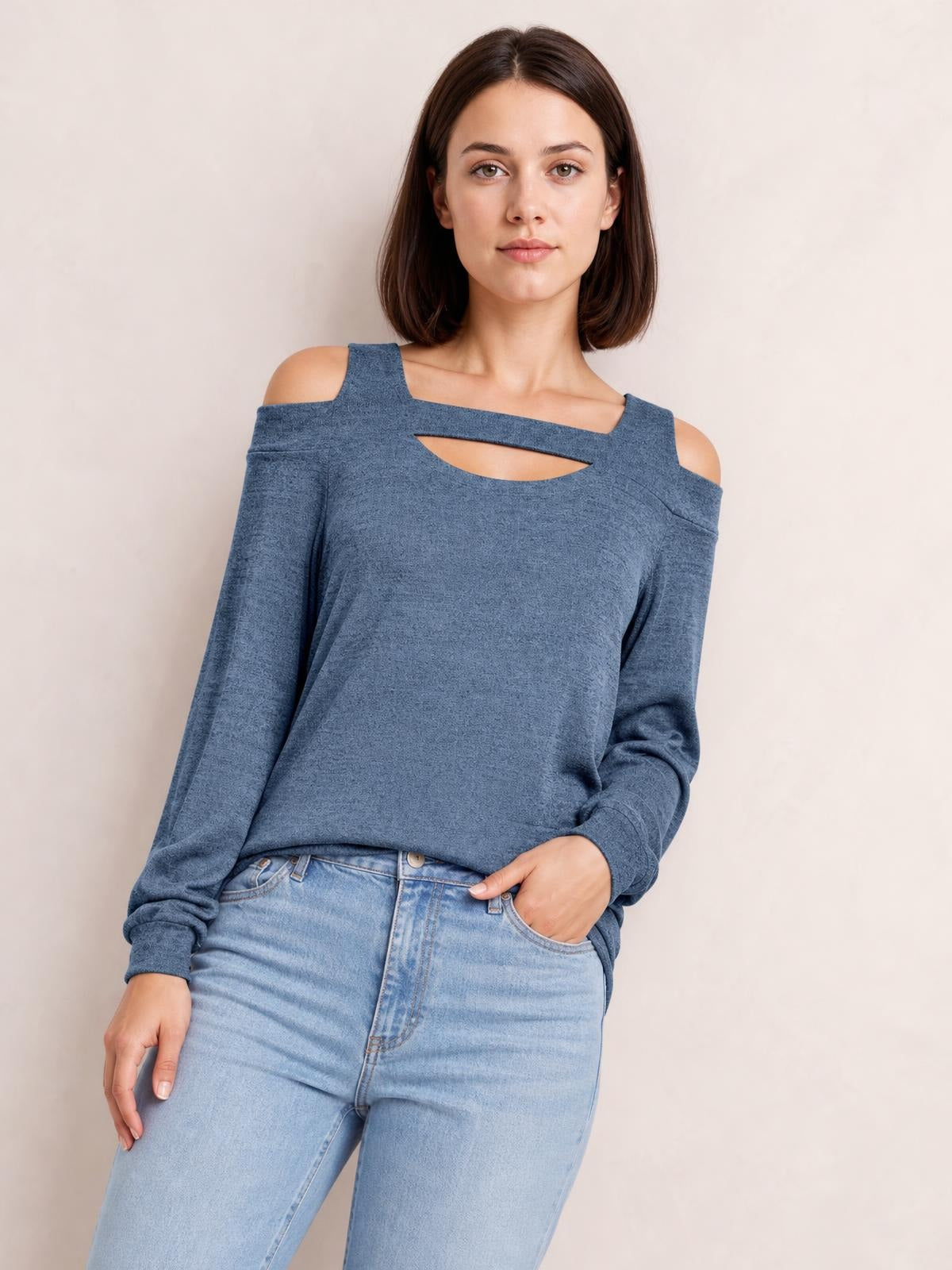 Model wears a blue solid cold-shoulder top with long sleeves, a square neckline, and a chest cutout, styled in a relaxed silhouette with one hand in her jeans pocket.