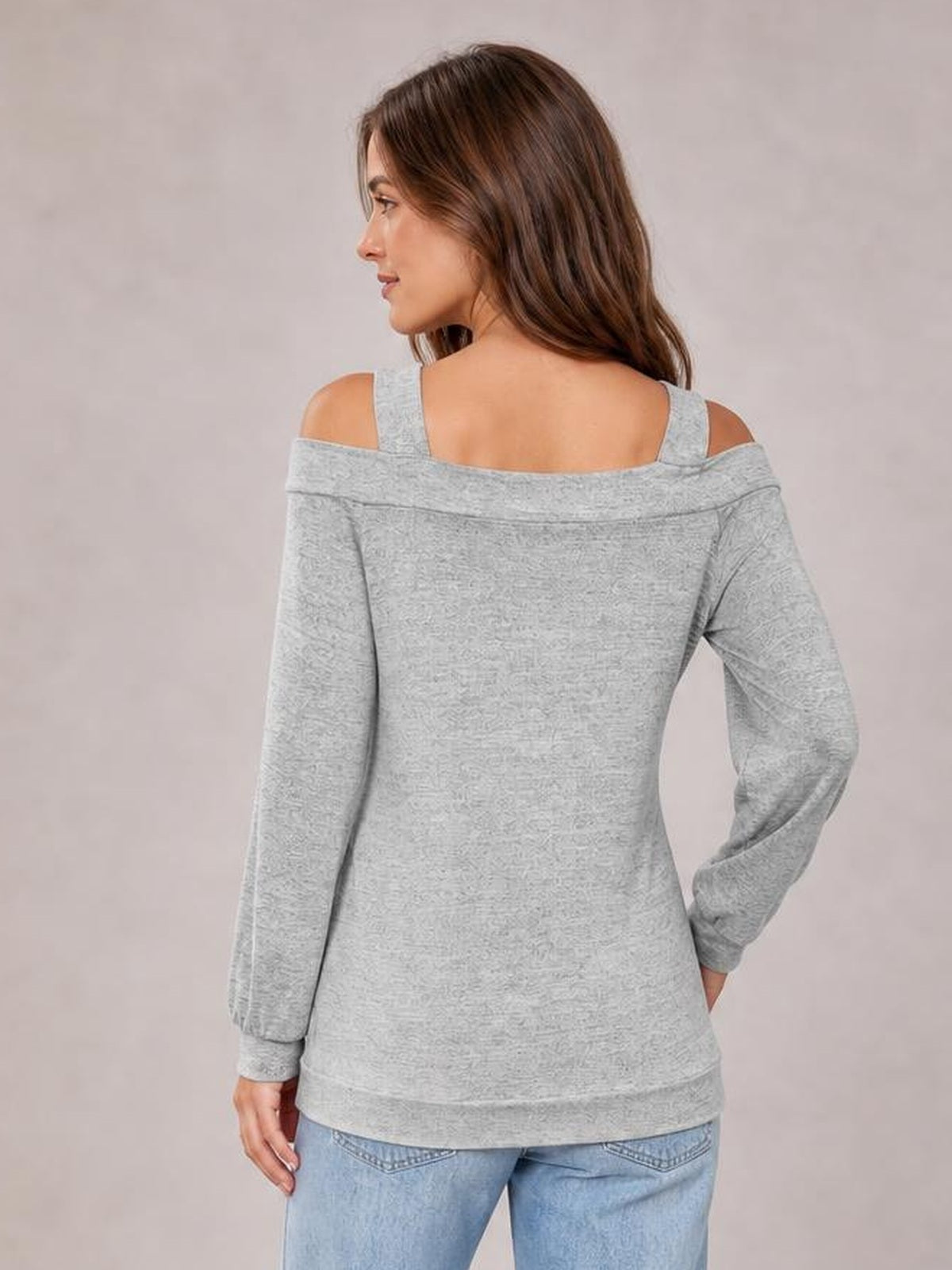 A model poses in a light gray solid cold-shoulder top with shoulder cutouts, long sleeves, a relaxed regular silhouette, and ribbed cuffs and hem.