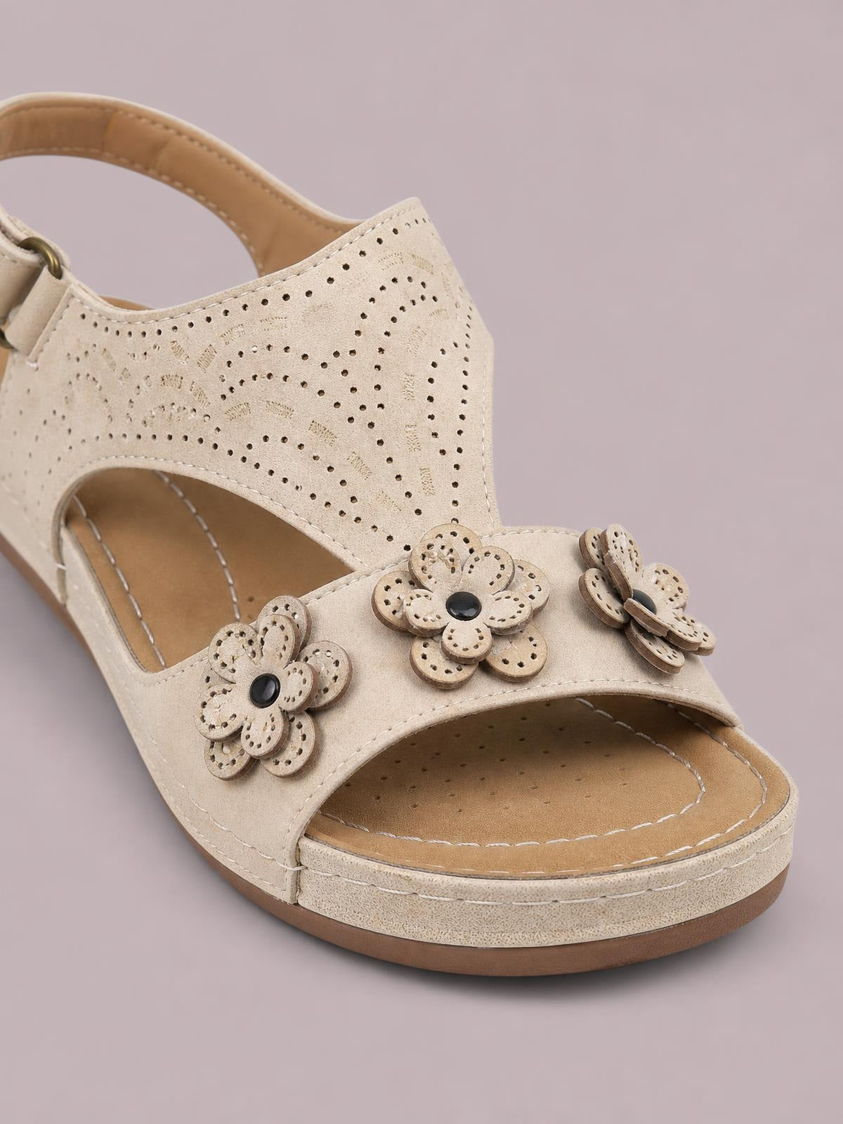 Beige cutout flower open-toe flat sandal with layered floral embellishments, perforated PU leather upper, stitched details, and a low rubber sole.