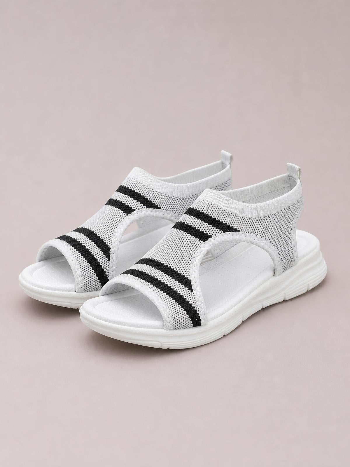 White mesh cutout peep toe sandals with black striped panels, open toes, ankle coverage, and flat cushioned soles.