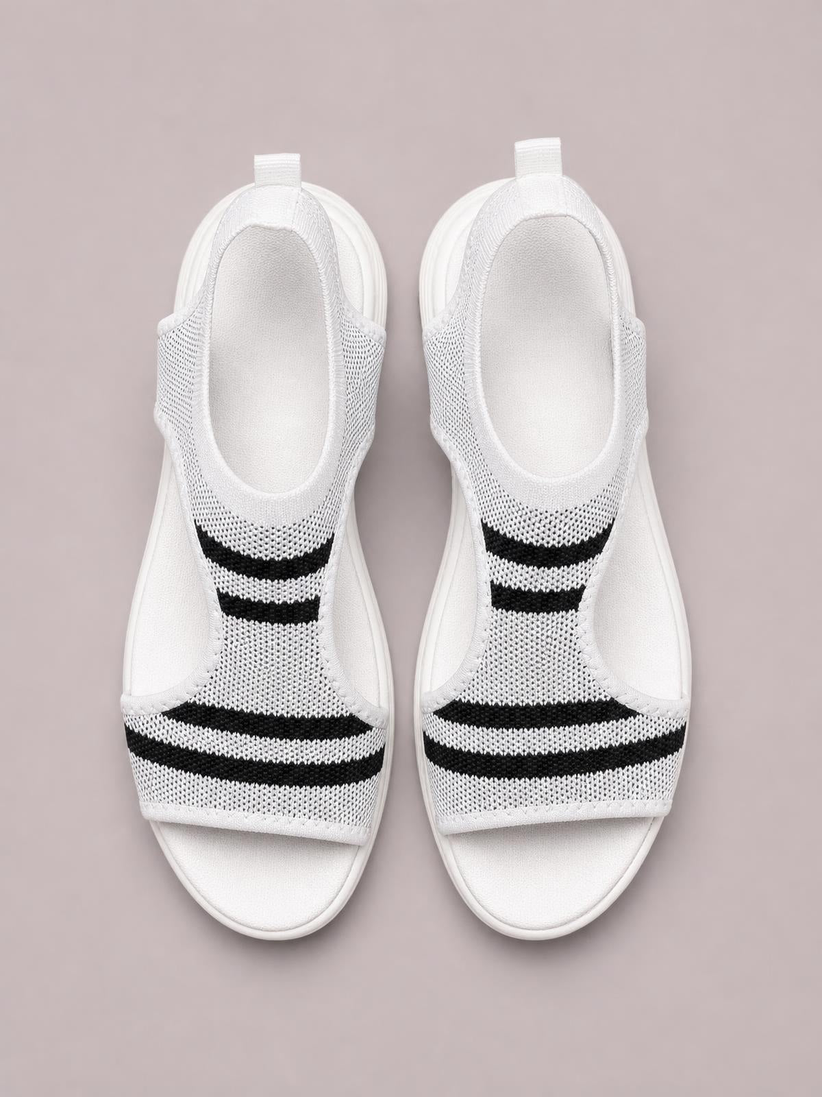 White cutout mesh peep toe sandals with black stripe detailing, open sides, cushioned footbeds, and flat soles shown from above.