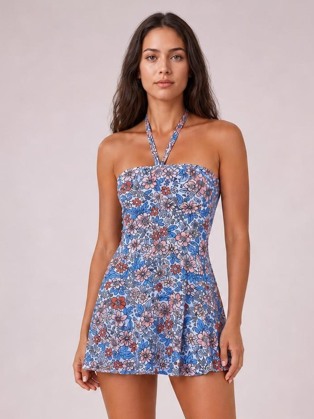 Front-facing model wears a blue floral printed halter neck one-piece swimsuit with a fitted bodice and softly flared skirt silhouette.
