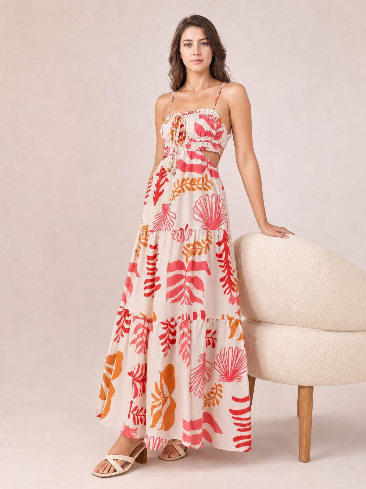 Model wears a printed sleeveless midi cami dress with thin straps, a ruched smocked bodice, side cutout, front tie, and flowing tiered skirt.