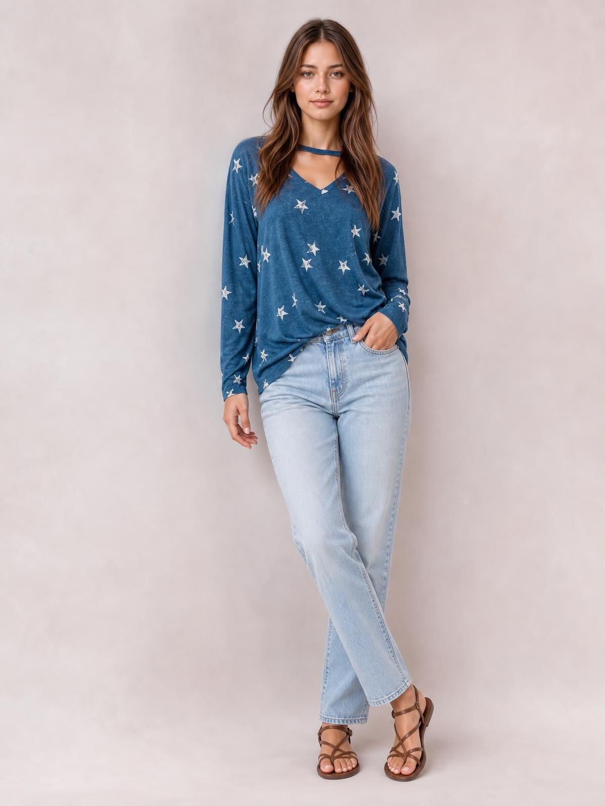 Model wears a blue star-print cutout round neck long sleeve T-shirt with a relaxed silhouette, standing with one hand in her jeans pocket.