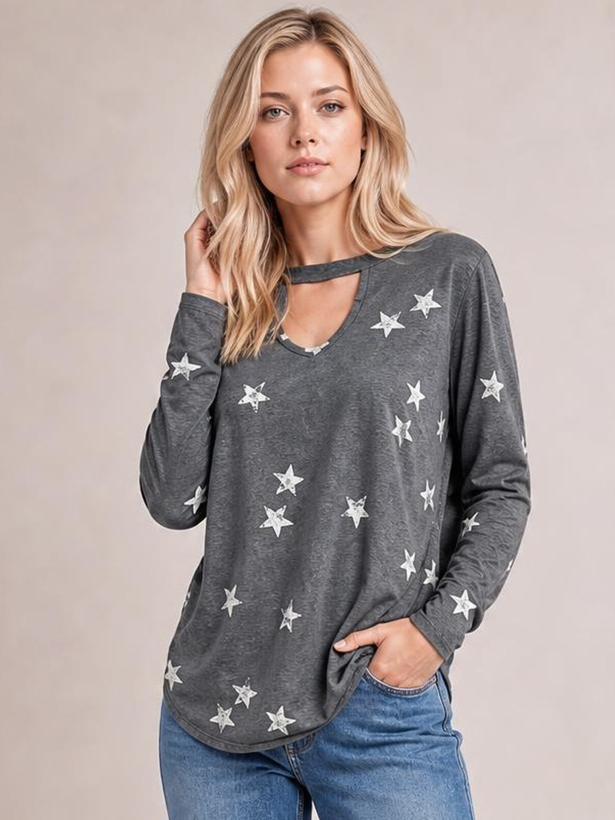Model poses in a relaxed gray cutout round neck long sleeve T-shirt with a loose silhouette and scattered white star print, one hand in her pocket.