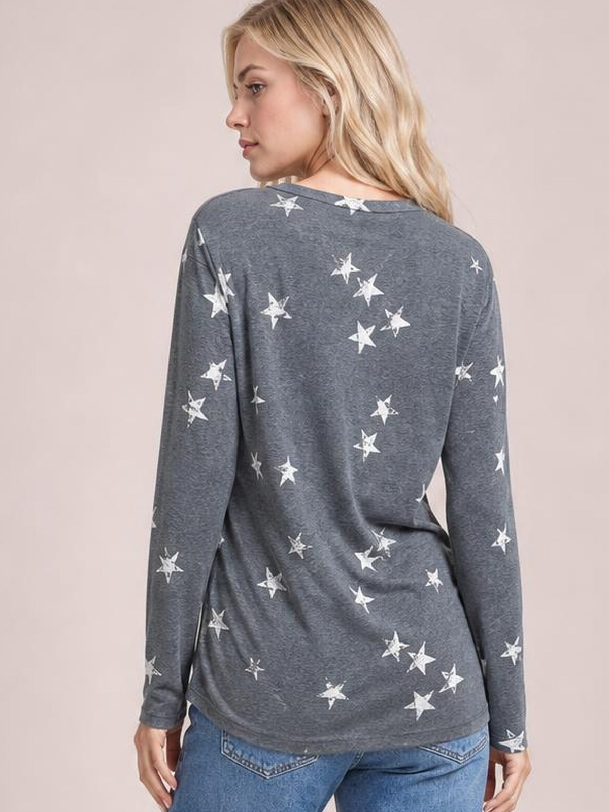 Model turns to show a gray star-print long-sleeve T-shirt with a round neckline and relaxed, straight silhouette.