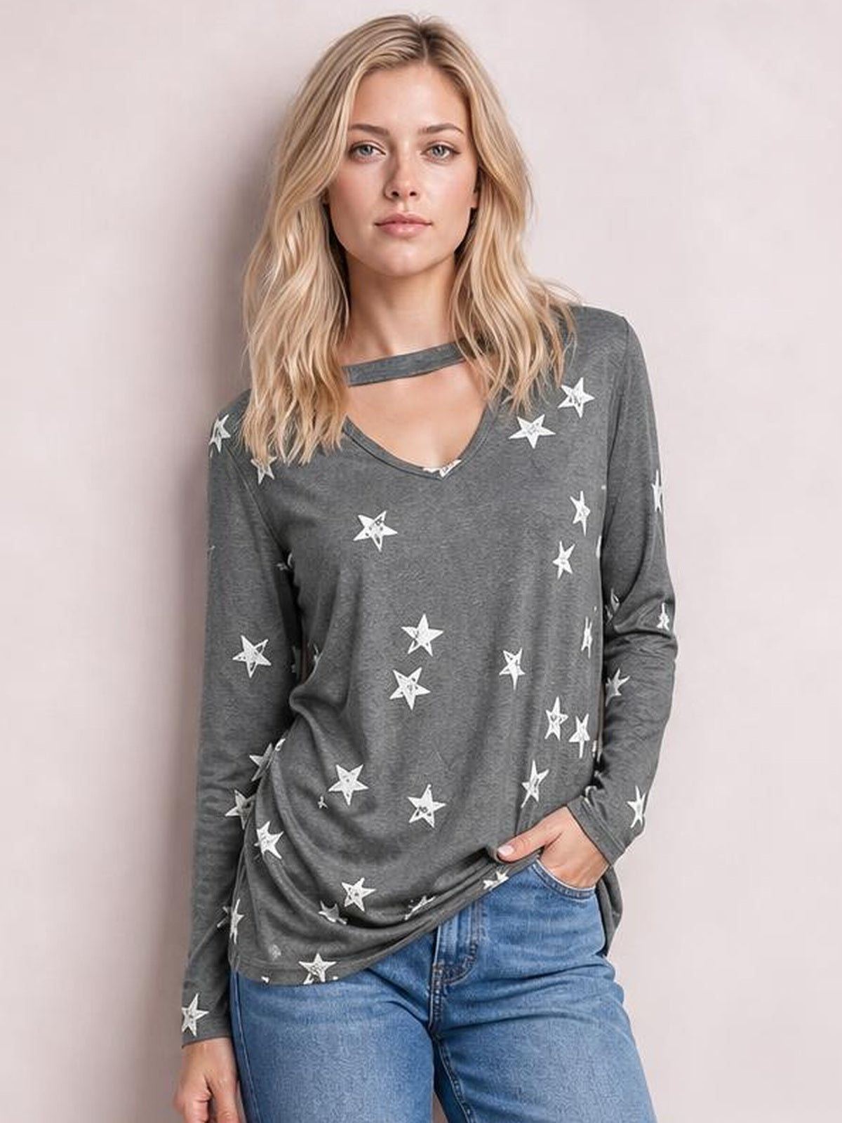 A model wears a gray star-print cutout round-neck long-sleeve T-shirt with a relaxed silhouette, standing with one hand in her jeans pocket.