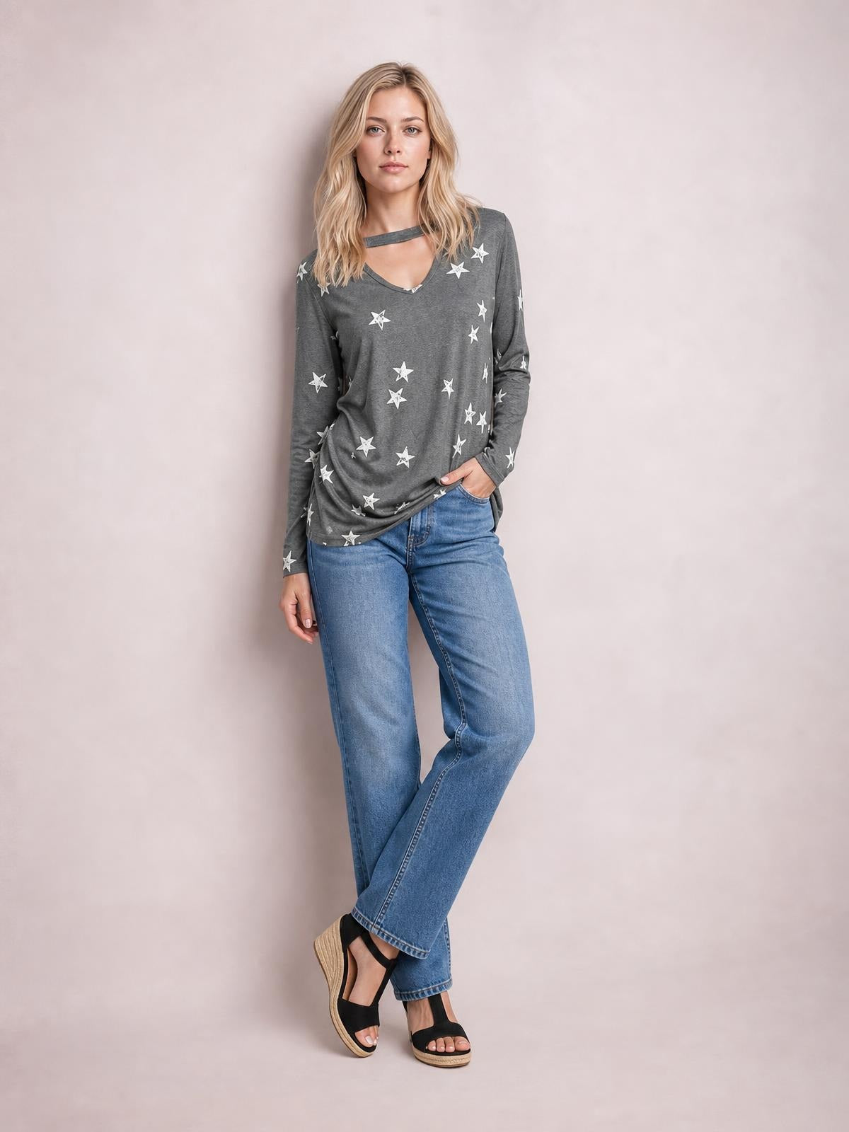 Model wears a gray cutout round-neck long-sleeve T-shirt with a relaxed silhouette, white star print, and hand tucked into a jeans pocket.