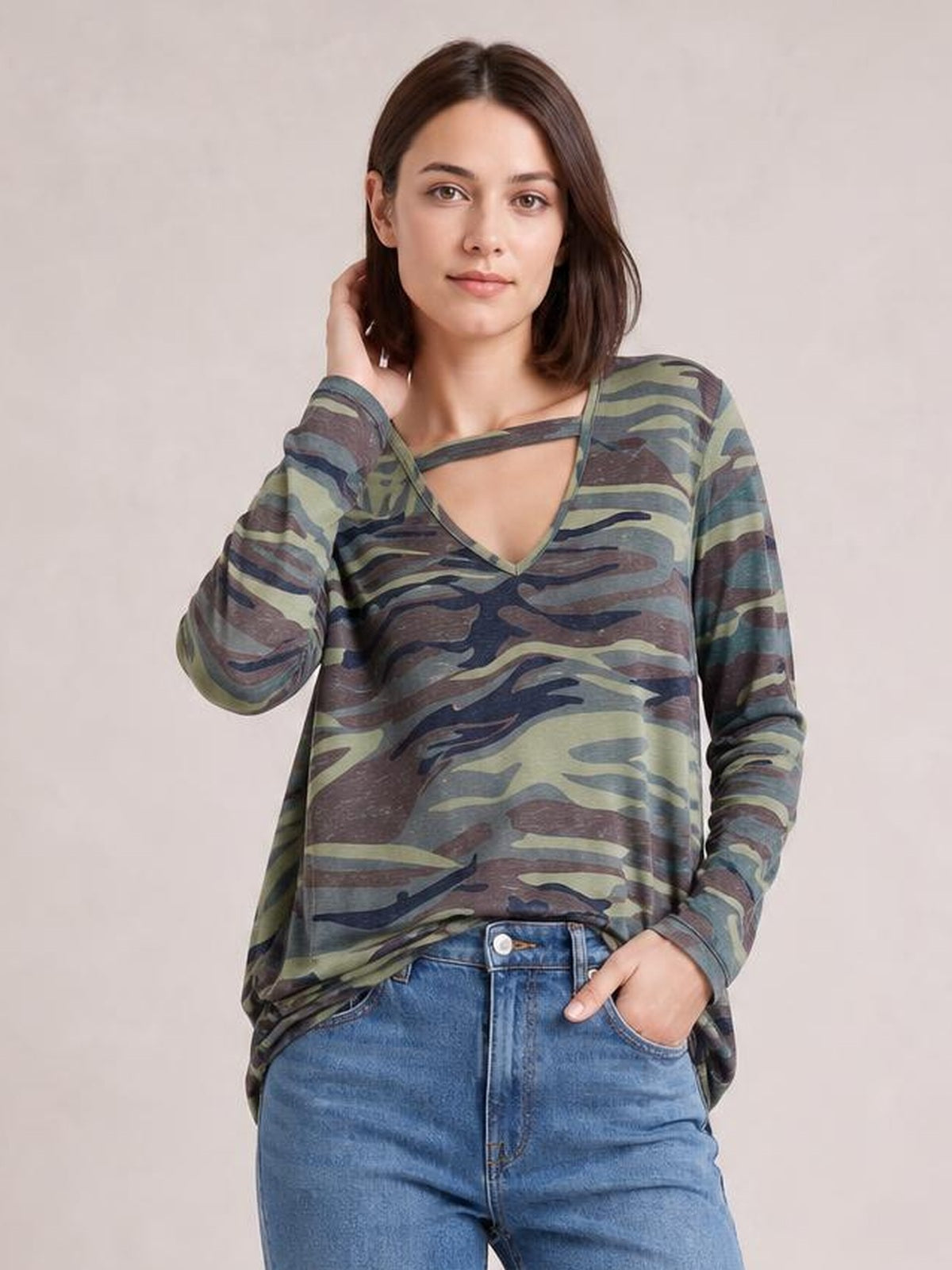 Model poses in an olive, brown, and navy camouflage long-sleeve T-shirt with a cutout neckline, V-shaped front, and relaxed silhouette.