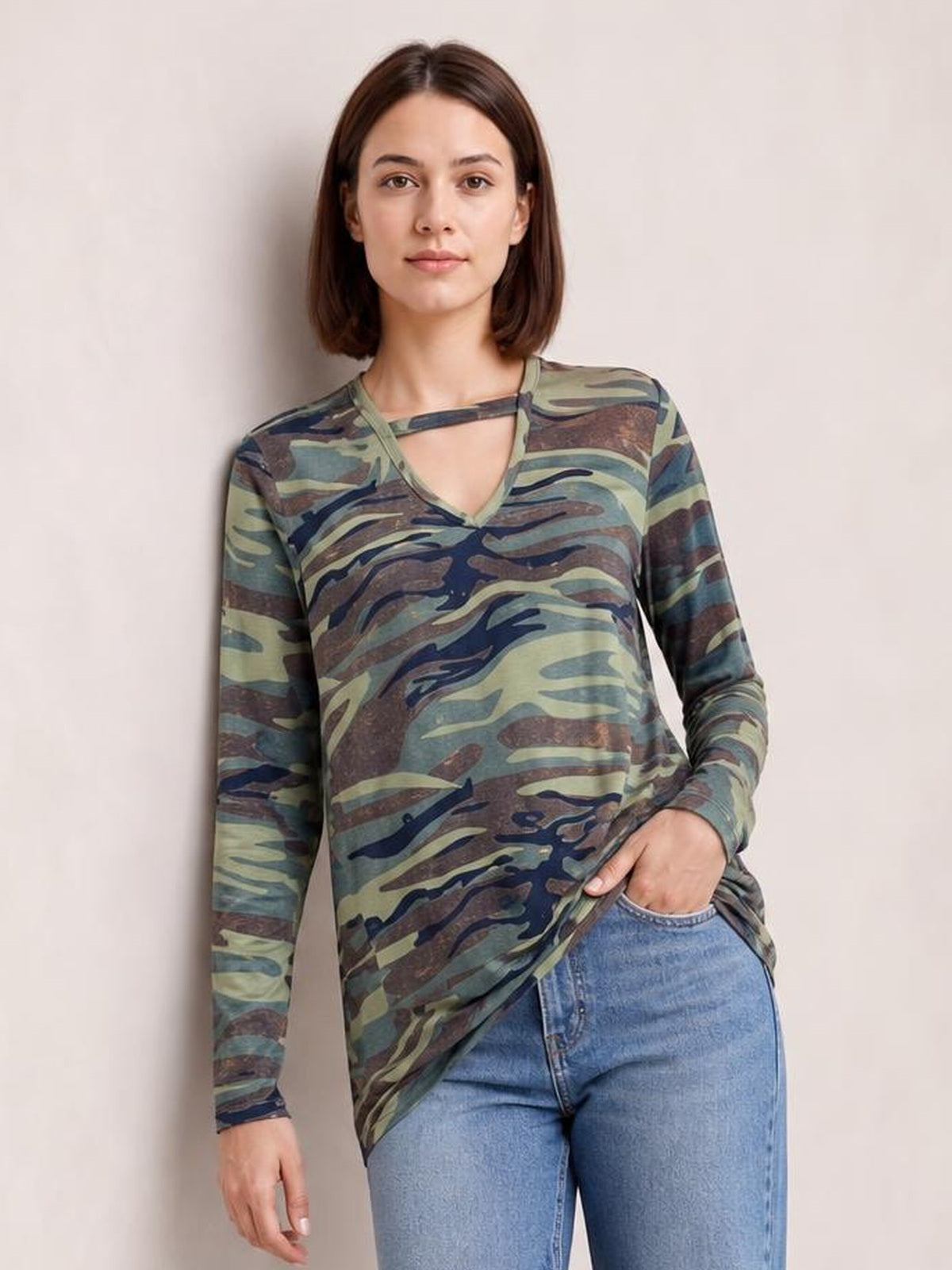 A model wears a camouflage-print cutout round neck long sleeve T-shirt with a relaxed silhouette, standing with one hand in her jeans pocket.