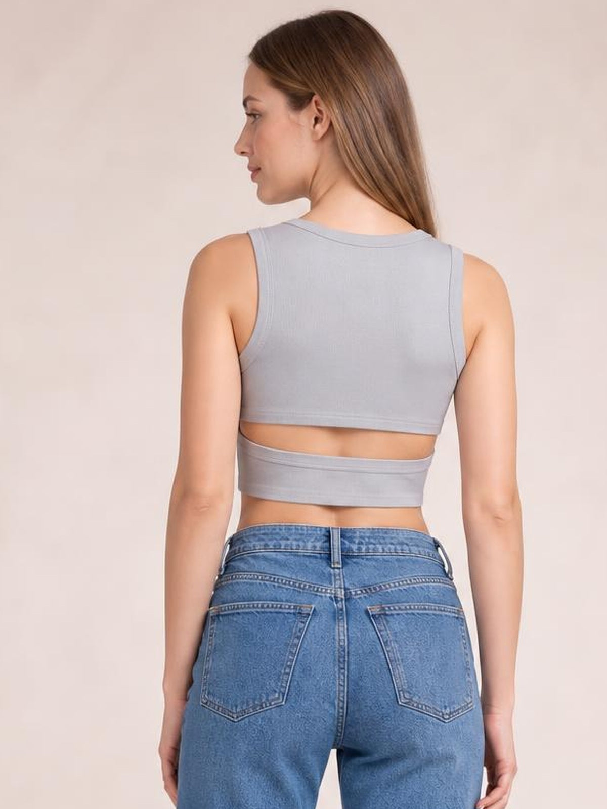 Model shown from behind wearing a light gray cutout round-neck tank with wide shoulder straps, cropped silhouette, and exposed midriff.