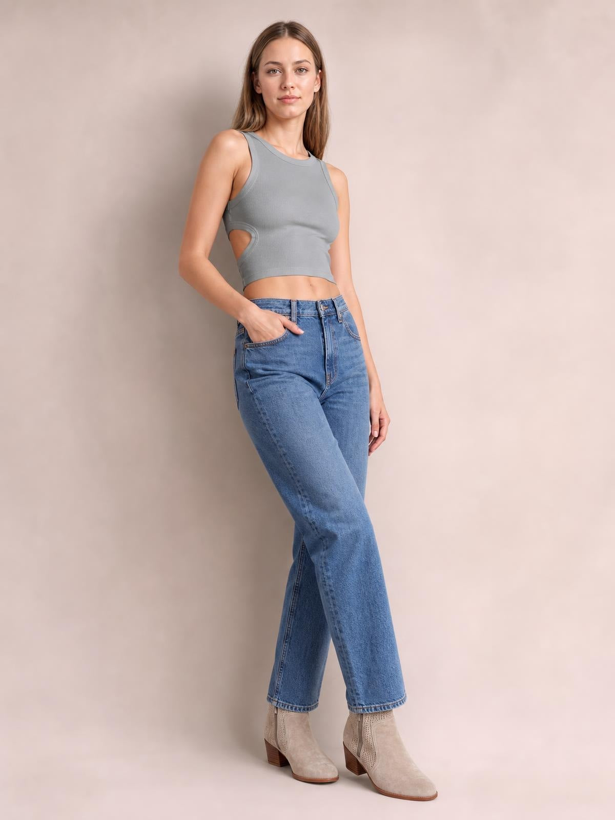 Model poses in a gray cutout round neck tank with a fitted cropped silhouette, ribbed construction, and wide shoulder straps.