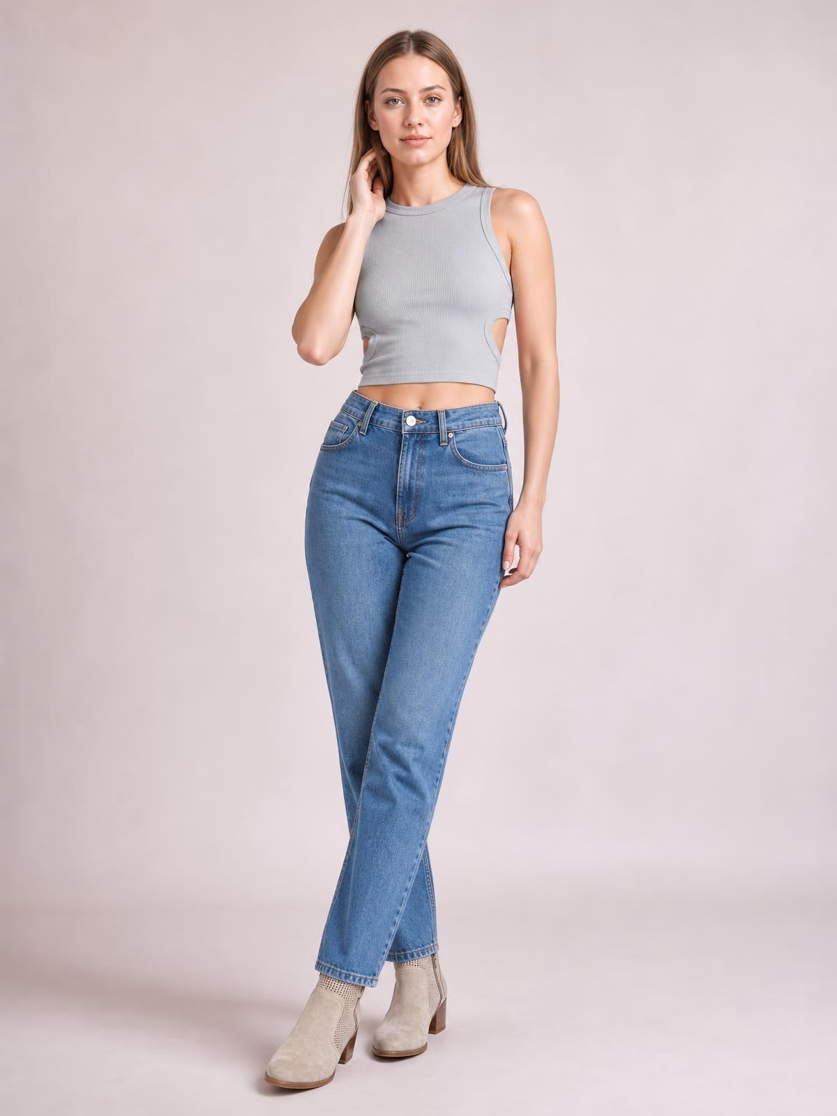 Model poses in a gray cutout round neck tank with a fitted cropped silhouette, wide shoulder straps, and side waist openings.