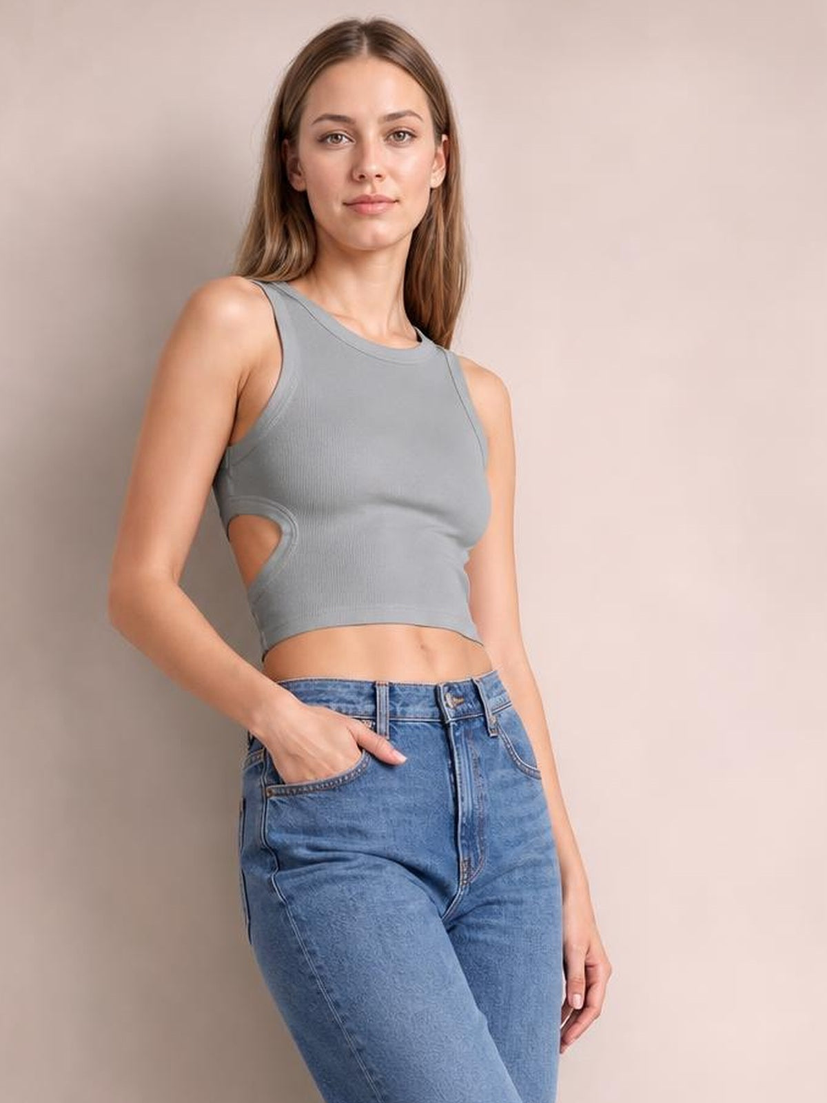 Model poses in a gray cutout round neck tank with wide shoulder straps, a fitted cropped silhouette, and a side waist opening.