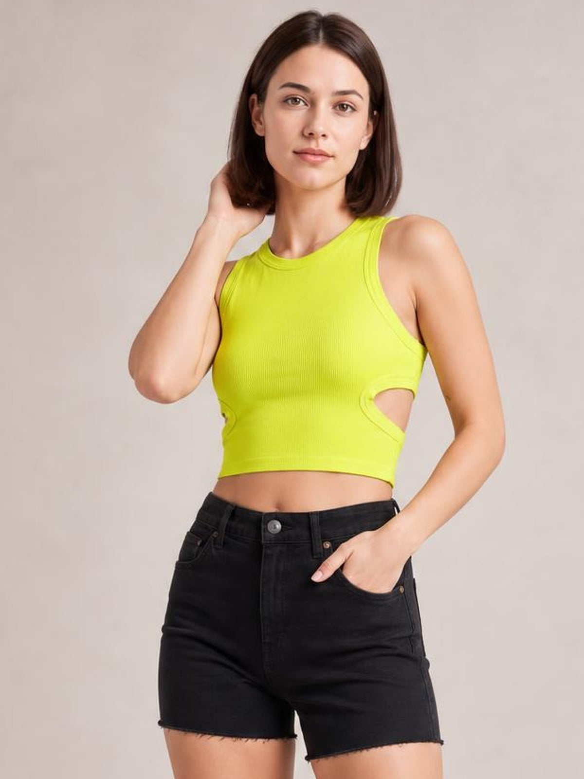 Model poses in a bright lime cutout round neck tank with wide shoulder straps, a fitted cropped silhouette, and side waist openings.