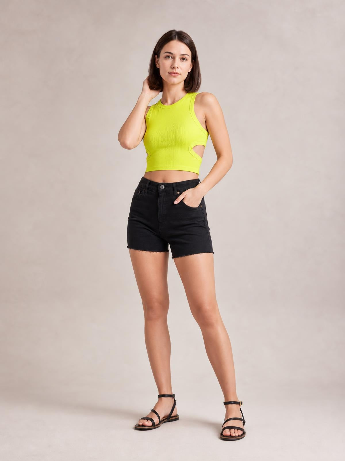 Model wears a lime green cutout round neck tank with a fitted cropped silhouette and wide shoulder straps, posing with one hand in her pocket.