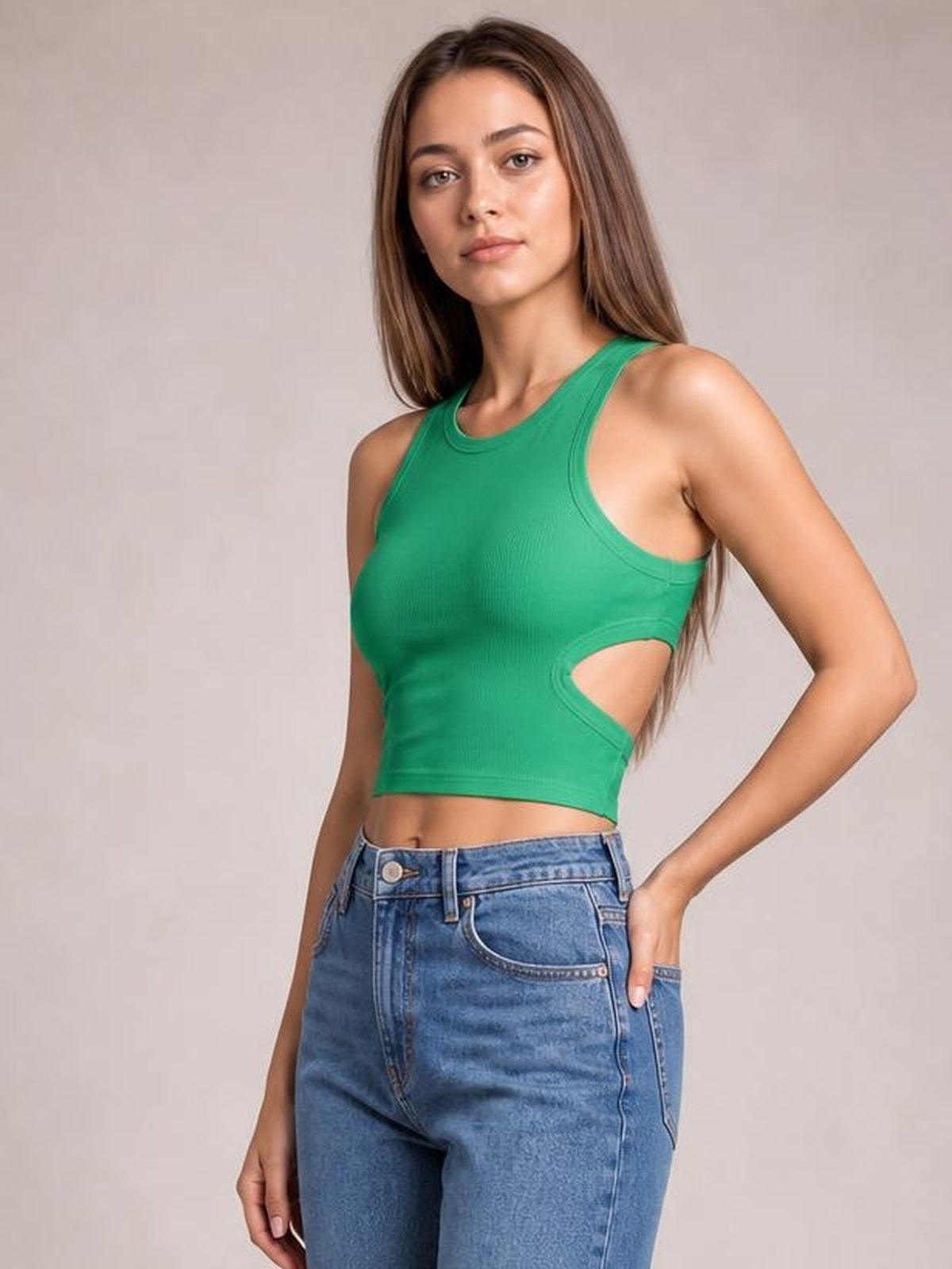 Model poses in a fitted green cutout round neck tank with wide shoulder straps, side waist opening, and cropped silhouette.