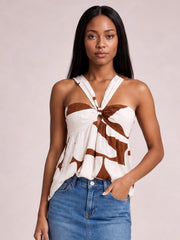 Model wearing a white and brown printed cutout sweetheart neck cami with twisted ruched detailing, wide straps, and a loose, flowing silhouette.