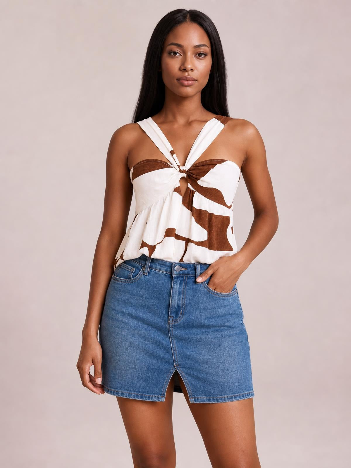 Model wears a white-and-brown Cutout Sweetheart Neck Cami with twisted center, ruched draping, and a relaxed silhouette, paired with a denim skirt.