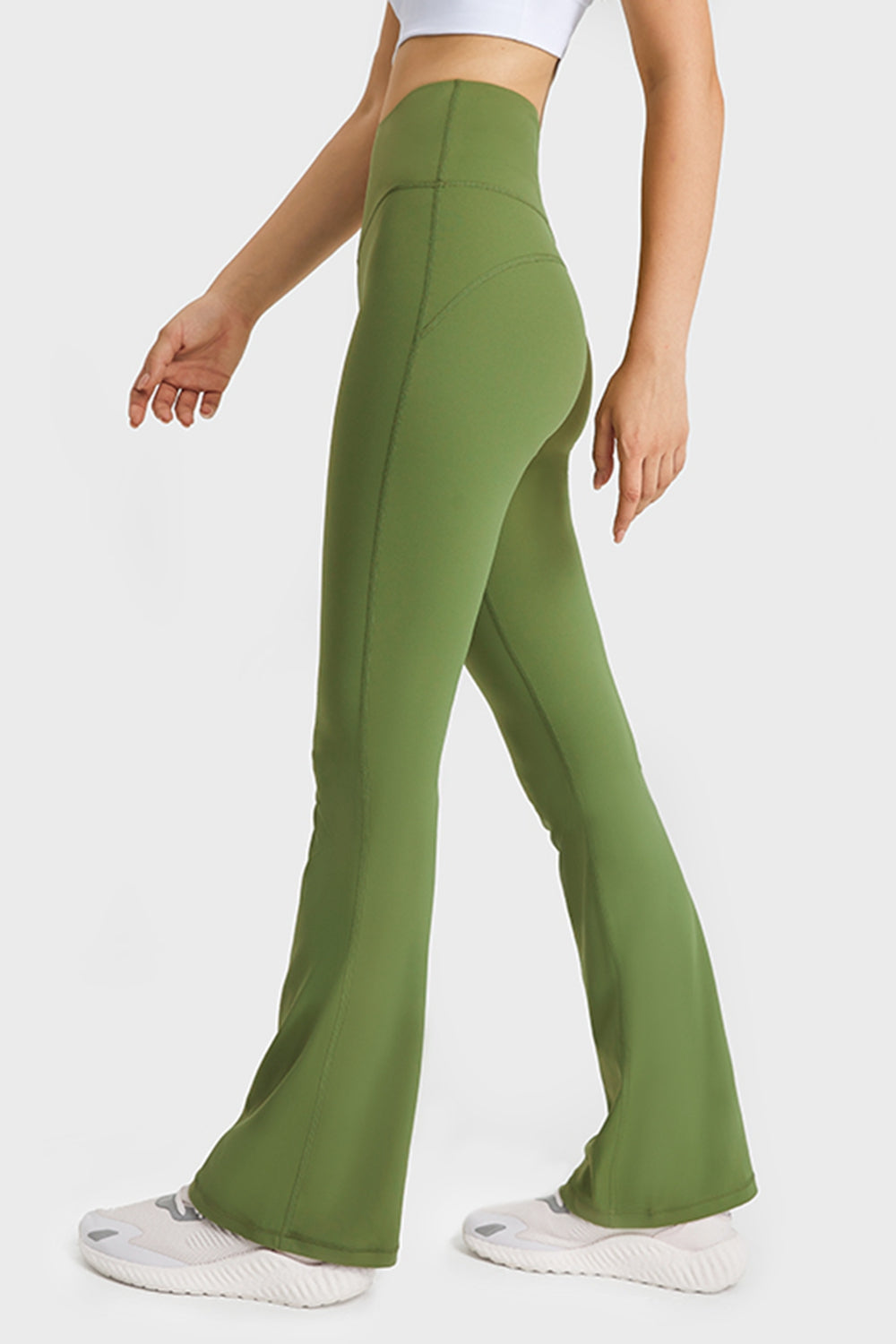 Model wearing solid olive green high-waisted flare yoga pants with a fitted silhouette, elastic waist, visible seam construction, and long flared legs.