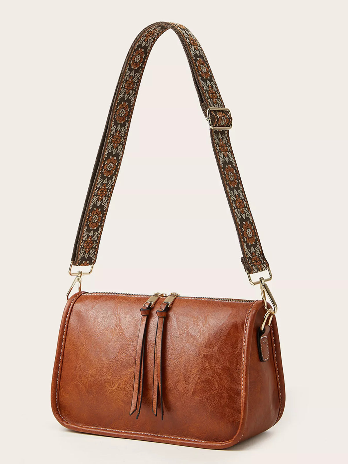 Small vintage-style brown PU leather crossbody bag with a rectangular silhouette, patterned adjustable strap, front tie details, stitched edges, and gold-tone hardware.