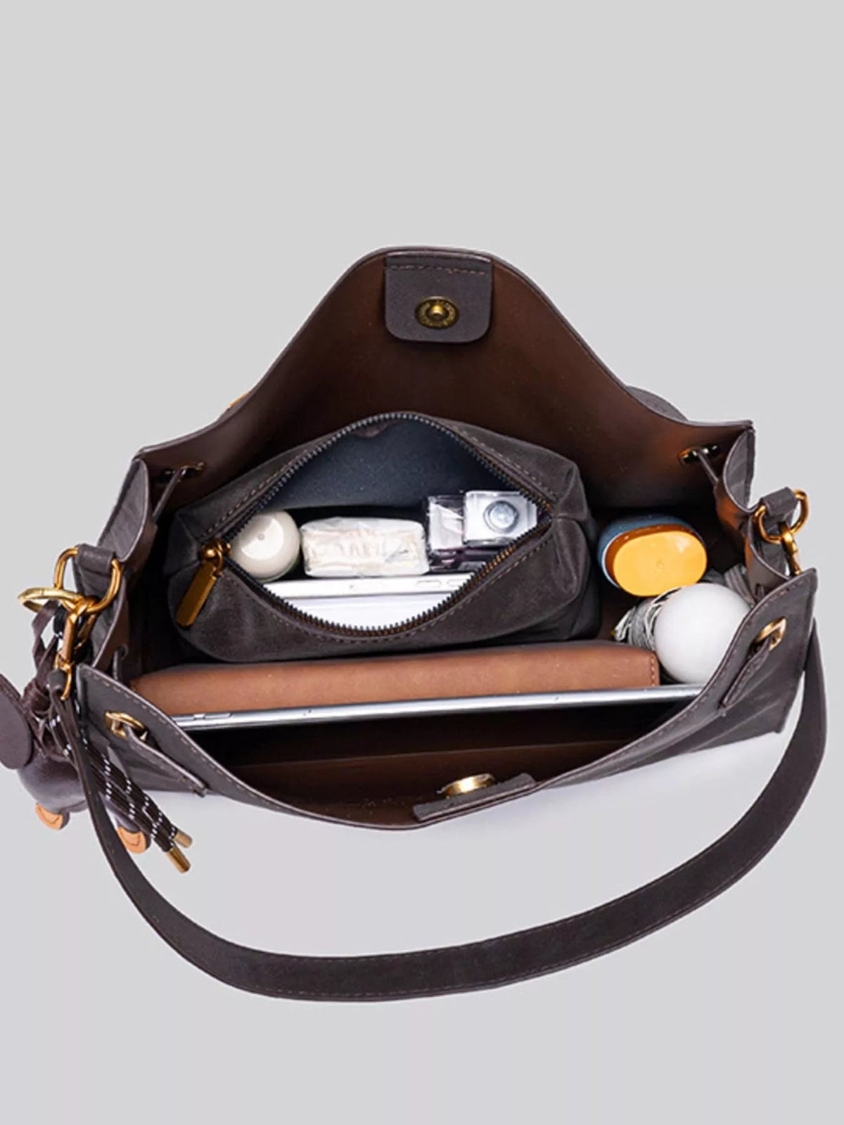 Open medium brown suede crossbody bag with a structured silhouette, gold-tone hardware, snap closure, and a spacious zippered interior.