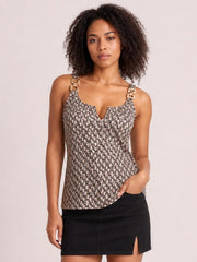 Model wears a beige and black printed notched tank with decorative buckle straps, a fitted silhouette, and a hand resting in her skirt pocket.