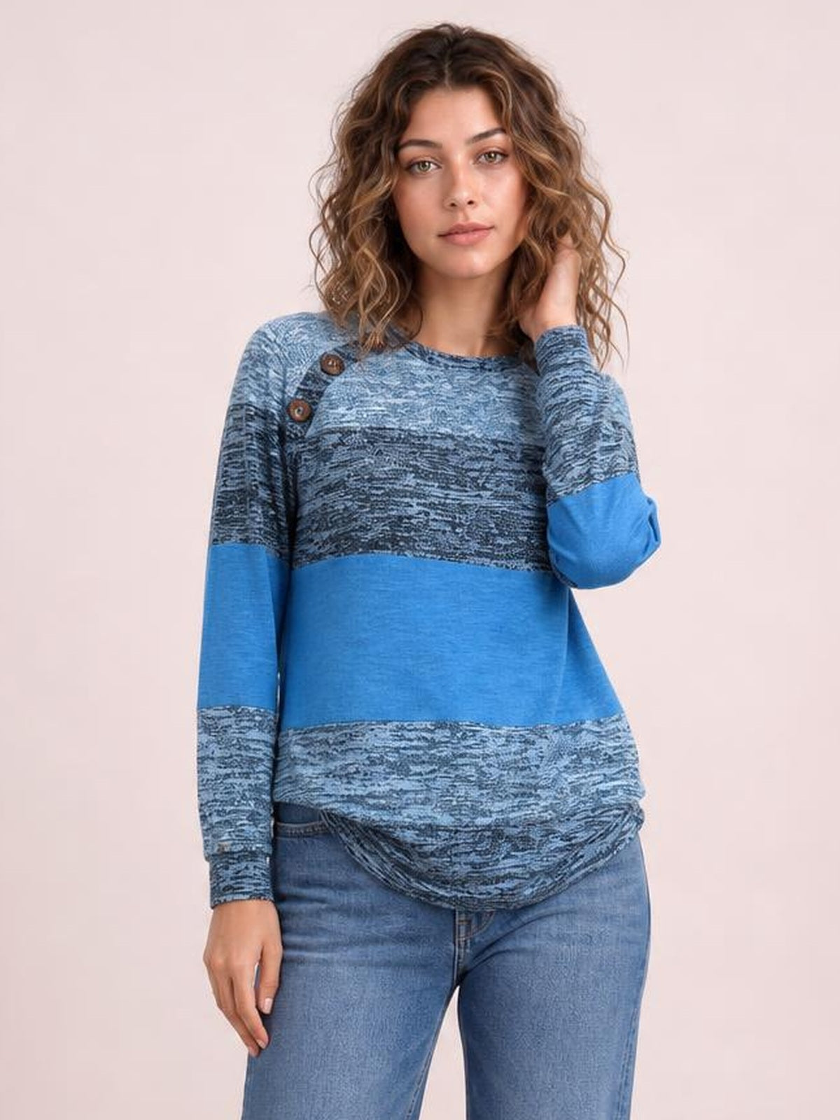 Model wears a blue contrast round-neck long-sleeve T-shirt with textured panels, decorative buttons at the shoulder, and a relaxed silhouette.