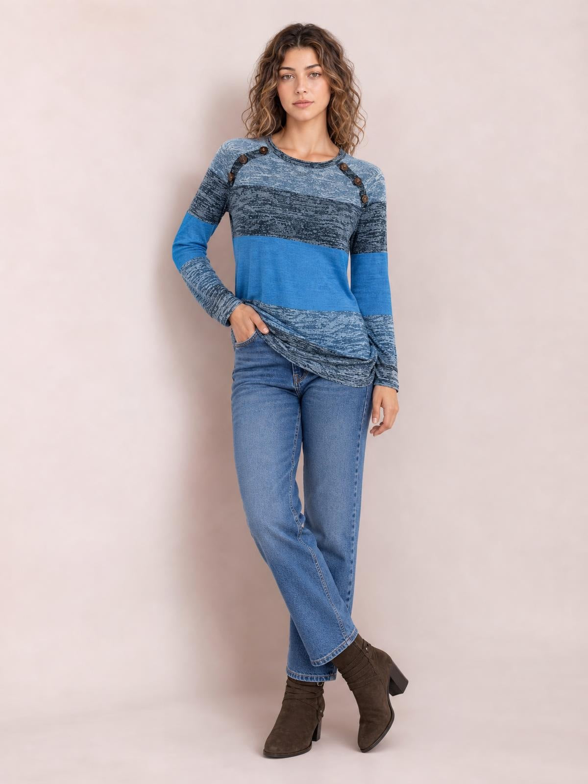 A model poses in a blue contrast long-sleeve T-shirt with a round neck, decorative shoulder buttons, textured panels, and a relaxed straight silhouette.