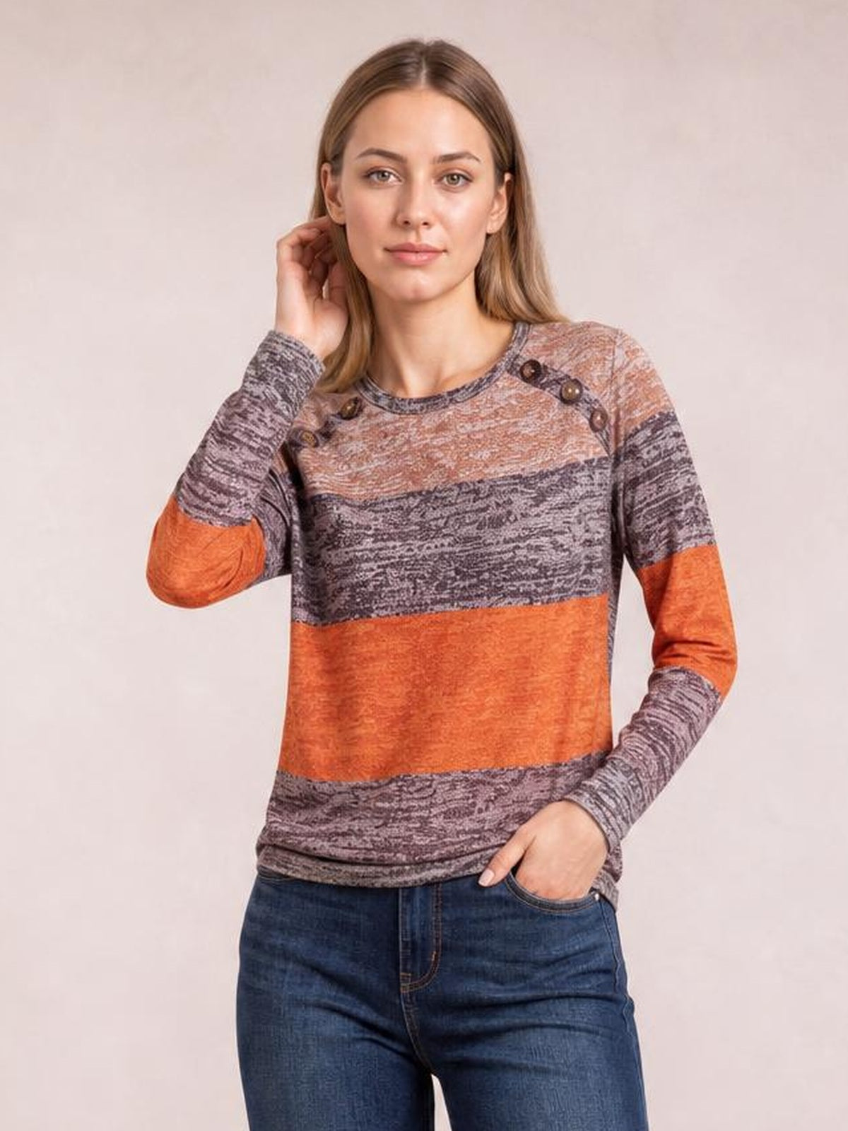 Model poses in a contrast gray, rust-orange, and mauve long-sleeve T-shirt with a round neck, decorative shoulder buttons, and a straight silhouette.
